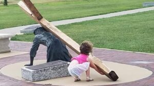 La bambina prova a sollevare la statua di Gesù che porta la croce: la foto diventa virale